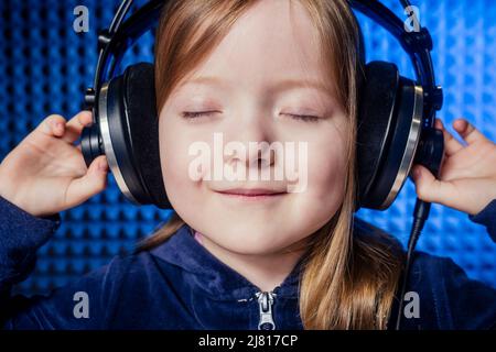 Mädchen Star Sängerin Künstler in einer schwarzen Bluse mit Kopfhörer Aufnahme neuer Song mit Mikrofon. Stockfoto