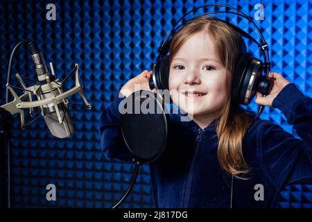 Mädchen Star Sängerin Künstler in einer schwarzen Bluse mit Kopfhörer Aufnahme neuer Song mit Mikrofon. Stockfoto