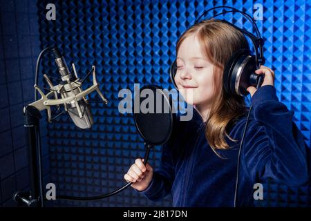 Mädchen Star Sängerin Künstler in einer schwarzen Bluse mit Kopfhörer Aufnahme neuer Song mit Mikrofon. Stockfoto