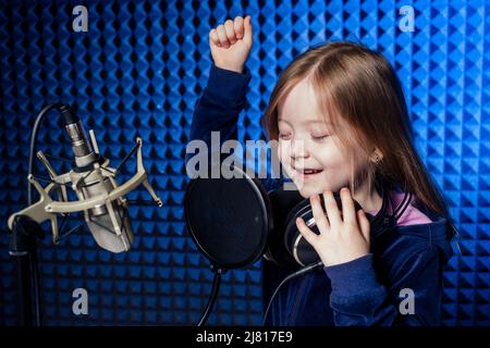 Mädchen Star Sängerin Künstler in einer schwarzen Bluse mit Kopfhörer Aufnahme neuer Song mit Mikrofon. Stockfoto