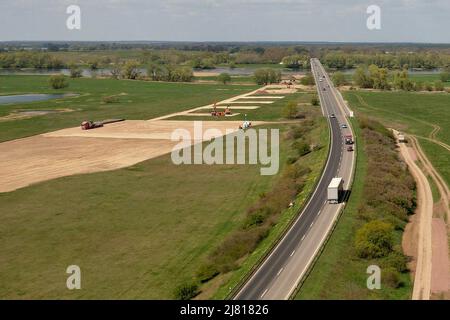 Seehausen, Deutschland. 29. April 2022. Blick auf die Brücke der Bundesstraße 189 über die Elbe Richtung Wittenberge. Daneben verläuft die Baustelle für die Elbbrücke entlang der Autobahn 14. Für den Neubau der Autobahn 14 zwischen der Anschlussstelle Seehausen-Nord (Sachsen-Anhalt) und Wittenberge (Brandenburg) beginnen in diesen Tagen die Arbeiten an der neuen Elbbrücke, die beide Länder verbindet. Zunächst beginnen südlich der Elbe die Arbeiten an den Fundamenten für die Pfeiler der Uferbrücke und des Abutments (Foto aufgenommen mit einer Drohne). Quelle: Peter Gercke/dpa/Alamy Live News Stockfoto