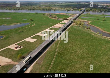 Seehausen, Deutschland. 29. April 2022. Blick auf die Brücke der Bundesstraße 189 über die Elbe Richtung Wittenberge. Daneben verläuft die Baustelle für die Elbbrücke entlang der Autobahn 14. Für den Neubau der Autobahn 14 zwischen der Anschlussstelle Seehausen-Nord (Sachsen-Anhalt) und Wittenberge (Brandenburg) beginnen in diesen Tagen die Arbeiten an der neuen Elbbrücke, die beide Länder verbindet. Zunächst beginnen südlich der Elbe die Arbeiten an den Fundamenten für die Pfeiler der Uferbrücke und des Abutments (Foto aufgenommen mit einer Drohne). Quelle: Peter Gercke/dpa/Alamy Live News Stockfoto