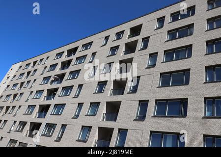 Blick auf ein modernes, mehrstöckiges Wohnapartment mit Blick auf den klaren blauen Himmel. Stockfoto
