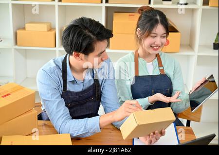 Paar tun ein Geschäft zusammen Konzept, männlich und weiblich Kleinunternehmen Eigentümer Überprüfung Online-Bestellungen und Verpackung des Produkts zusammen. Stockfoto