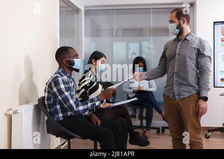 HR-Abteilungsleiter erhält arbeitslosen Mann Lebenslauf im Wartezimmer des Marketingunternehmens. afroamerikanische Person, die sich für einen Geschäftsmann bewerben kann, während sie in der Lobby sitzt. Stockfoto