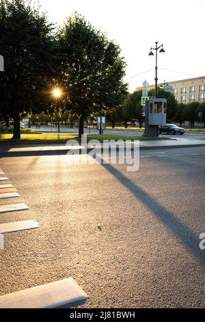 Die untergehende Sonne scheint durch die Bäume in der Stadt. Vorderansicht. Stockfoto