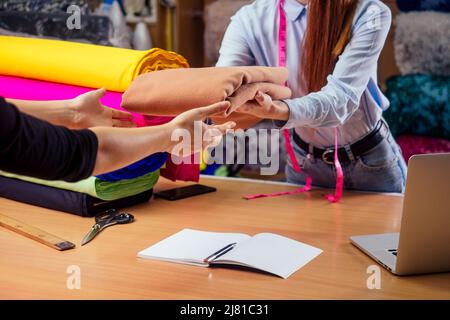 Rotschopf Ingwer Schneiderin Frau geben Gewebe geschnitten, um Kunden in Textil-Shop Stockfoto