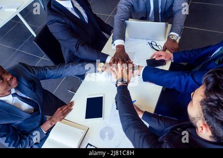 Chef-Afro-Geschäftsleute im Gespräch mit arabischen und indischen Partner Kollegen, multiethnische Team sitzt an einem Tisch mit einem Laptop und Dokumente im Büro Stockfoto