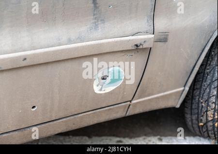 Während des Krieges wurde ein Auto geschält. Durch Löcher von Schrapnel und Kugeln an der Autotür. Russischer Angriff auf die Ukraine im Jahr 2022. Beschuss von Zivilisten. War c Stockfoto