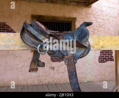 Alter Westernsattel auf einem Baumstamm zum Reiten. Nahaufnahme. Stockfoto