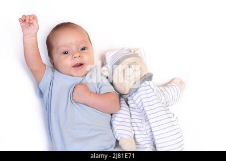 Das Baby liegt in einer Krippe mit einem Teddybär. Das Baby ist 0-3 Monate alt. Ruhiges Kind. Ein Artikel über Spielzeug für Kinder. Ein weiches Spielzeug. Speicherplatz Kopieren Stockfoto