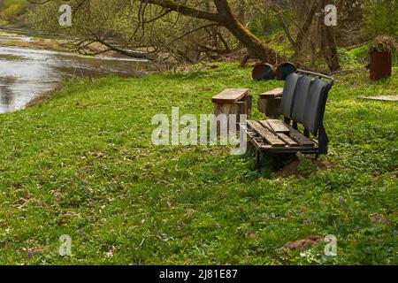 Eine Bank aus einem alten, kaputten Autositz am Flussufer Stockfoto