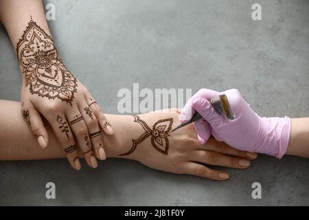 Mehndi Meister Zeichnung Henna Tattoo auf weibliche Hand im Salon Stockfoto