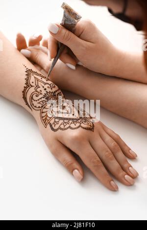 Mehndi Meister Zeichnung Henna Tattoo auf weibliche Hand im Salon Stockfoto