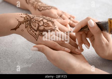 Mehndi Meister Zeichnung Henna Tattoo auf weibliche Hand im Salon Stockfoto