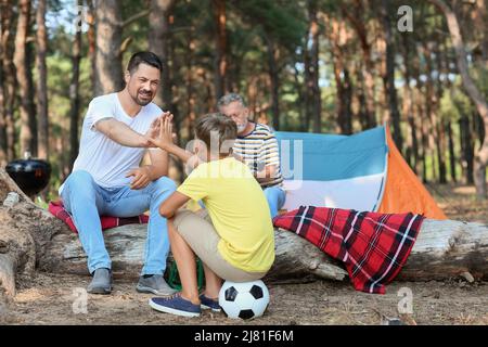 Ein hübscher Mann, der seinem kleinen Sohn im Wald High-Five gab Stockfoto