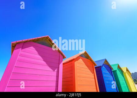 Lebendige bunte Holzhütten am klaren blauen Himmel mit Kopierfläche Stockfoto