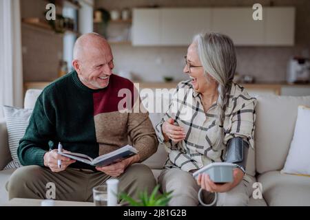 Seniorenpaar zu Hause, das den Blutdruck misst. Stockfoto