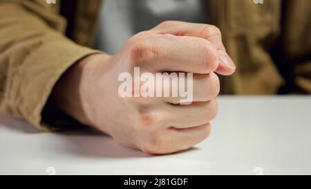 Ein wütender Arbeiter trifft den Tisch, während die Faust im Büro sitzt Stockfoto
