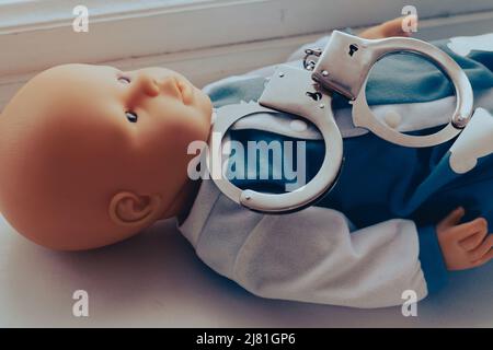 Baby Puppe liegt mit Handschellen. Kinderkriminalität Konzept. Hochwertige Fotos Stockfoto