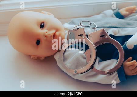 Baby Puppe liegt mit Handschellen. Kinderkriminalität Konzept. Hochwertige Fotos Stockfoto