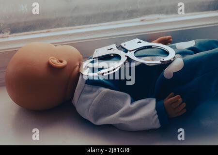 Baby Puppe liegt mit Handschellen. Kinderkriminalität Konzept. Hochwertige Fotos Stockfoto