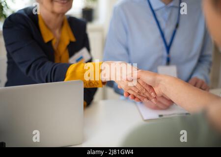 Freiwillige Helferinnen von Frauen und Männern, die der ukrainischen Frau beim Ausfüllen von Formularen im Asylzentrum helfen. Stockfoto