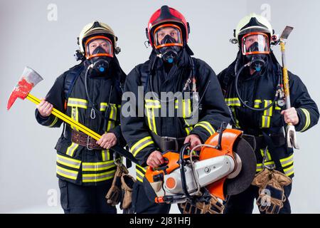 Portrait von drei Feuerwehrmännern stehen zusammen weißen Hintergrund Studio Stockfoto