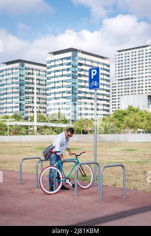 Junger Mann parkt Fahrrad auf der Stadtstraße Stockfoto