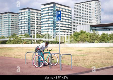 Junger Mann parkt Fahrrad auf der Stadtstraße Stockfoto