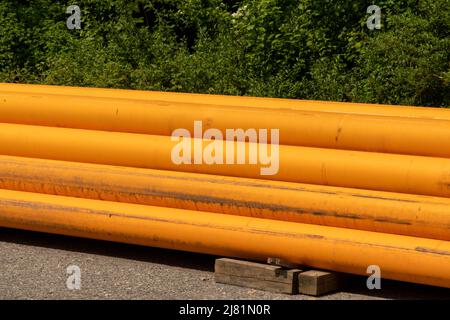 Auf einer Baustelle werden orangefarbene Leitungsrohre auf Lager gelegt Stockfoto