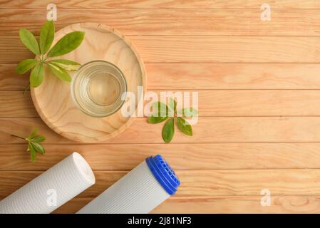 Umkehrosmose-System Wasserreinigungskonzept mit Glas gefüllt mit gereinigtem Wasser und Filtern auf Holztisch. Draufsicht. Horizontale Zusammensetzung. Stockfoto