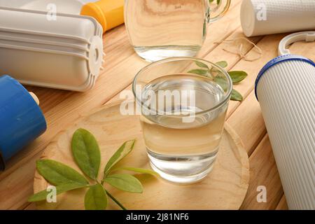 Glas gefiltertes Wasser mit Umkehrosmose-Anlage mit Filtern auf Holztisch. Erhöhte Ansicht. Horizontale Zusammensetzung. Stockfoto