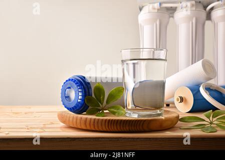 Glas von gereinigtem Wasser mit Haushaltsgeräten und umweltfreundlichen Filtern auf Holztisch isoliert Hintergrund mit Osmotizer Ausrüstung. Fro Stockfoto