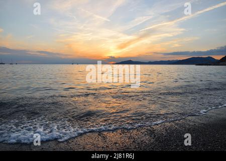 Wunderbarer Sonnenuntergang mit Lichtern, die sich im Meer und Himmel spiegeln, schafft eine magische Atmosphäre Stockfoto