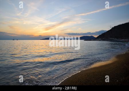 Wunderbarer Sonnenuntergang mit Lichtern, die sich im Meer und Himmel spiegeln, schafft eine magische Atmosphäre Stockfoto