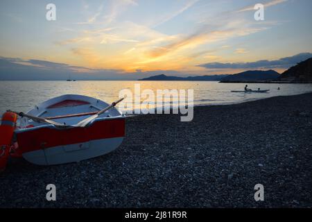 Wunderbarer Sonnenuntergang mit Lichtern, die sich im Meer und Himmel spiegeln, schafft eine magische Atmosphäre Stockfoto