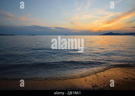 Wunderbarer Sonnenuntergang mit Lichtern, die sich im Meer und Himmel spiegeln, schafft eine magische Atmosphäre Stockfoto