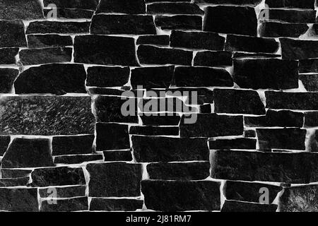 Schwarze Ziegelwand mit Top-Beleuchtungseffekt. Hintergrundfotostruktur Stockfoto