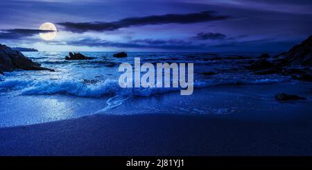 Leerer Strand in der Nacht. Schöne Landschaft am Meer. Wellen waschen den Sand und Steine am Ufer. Wolken glühen im Vollmondlicht. Ruhigen Sommer V Stockfoto