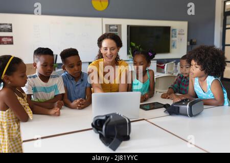 Kaukasische junge Lehrerin zeigt afroamerikanischen Grundschülerinnen in der Klasse einen Laptop Stockfoto