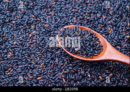 Ein Stapel schwarzen Reises und schwarzen Reises in einem Holzlöffel. Stockfoto