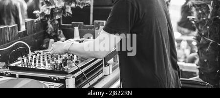 DJ spielt Musik in der Cocktailbar im Freien - Fokus auf linke Hand - Schwarz-Weiß-Schnitt Stockfoto