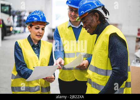 Multiethnische Ingenieure arbeiten in der Roboterfabrik - Industrie- und Technologiekonzept - Fokus auf afrikanisches Menschengesicht Stockfoto