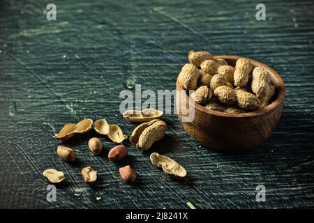 Erdnüsse mit Schale in Schale auf schwarzem Hintergrund Stockfoto