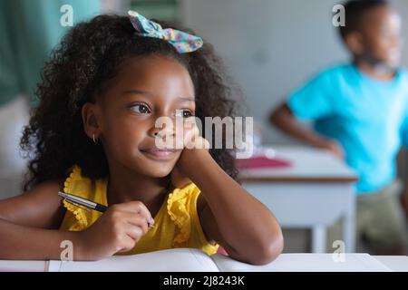 Nahaufnahme eines nachdenklichen afroamerikanischen Grundschulmädchen, das im Klassenzimmer am Schreibtisch sitzt Stockfoto