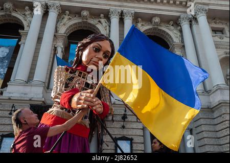 Amal, eine riesige Marionette, die ein neun Jahre altes syrisches Flüchtlingsmädchen darstellt, das beim Besuch im Zentrum von Lemberg die ukrainische Flagge hält. Die 3,5 Meter lange Riesenpuppe feiert die menschliche Migration und ist mehr als 8000 Kilometer von der syrischen türkischen Grenze durch Europa bis nach Großbritannien gereist. Als Teil der Bewegung wurde Amal zu jungen Flüchtlingen in der Ukraine gebracht und ist jetzt im Zentrum von Lemberg zu sehen. Russland marschierte am 24. Februar 2022 in die Ukraine ein und löste damit den größten militärischen Angriff in Europa seit dem Zweiten Weltkrieg aus Stockfoto