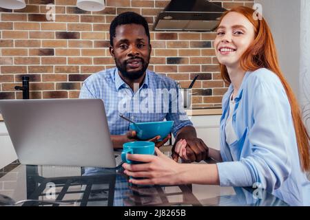 kaukasische rothaarige Frau und afromännlicher beim Frühstück zu Hause Stockfoto
