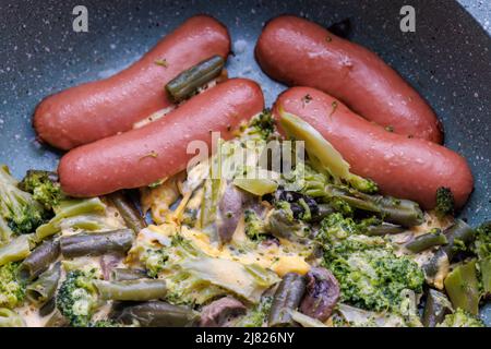Gebratene Würstchen und Gemüse mit Pilzen und Hühnereier auf einer Pfanne Stockfoto