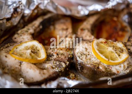 Gebackene Silberkarpfen-Steaks. Im Ofen in Folie mit Zitrone und Gewürzen gegartes Fischstück. Stockfoto